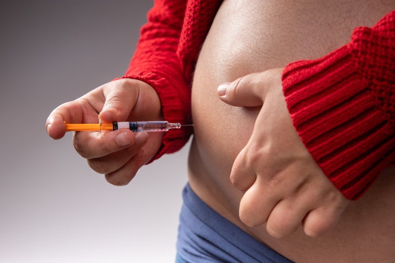 A pregnant woman injects herself a blood thinner with a syringe into her belly to prevent blood clots during pregnancy.